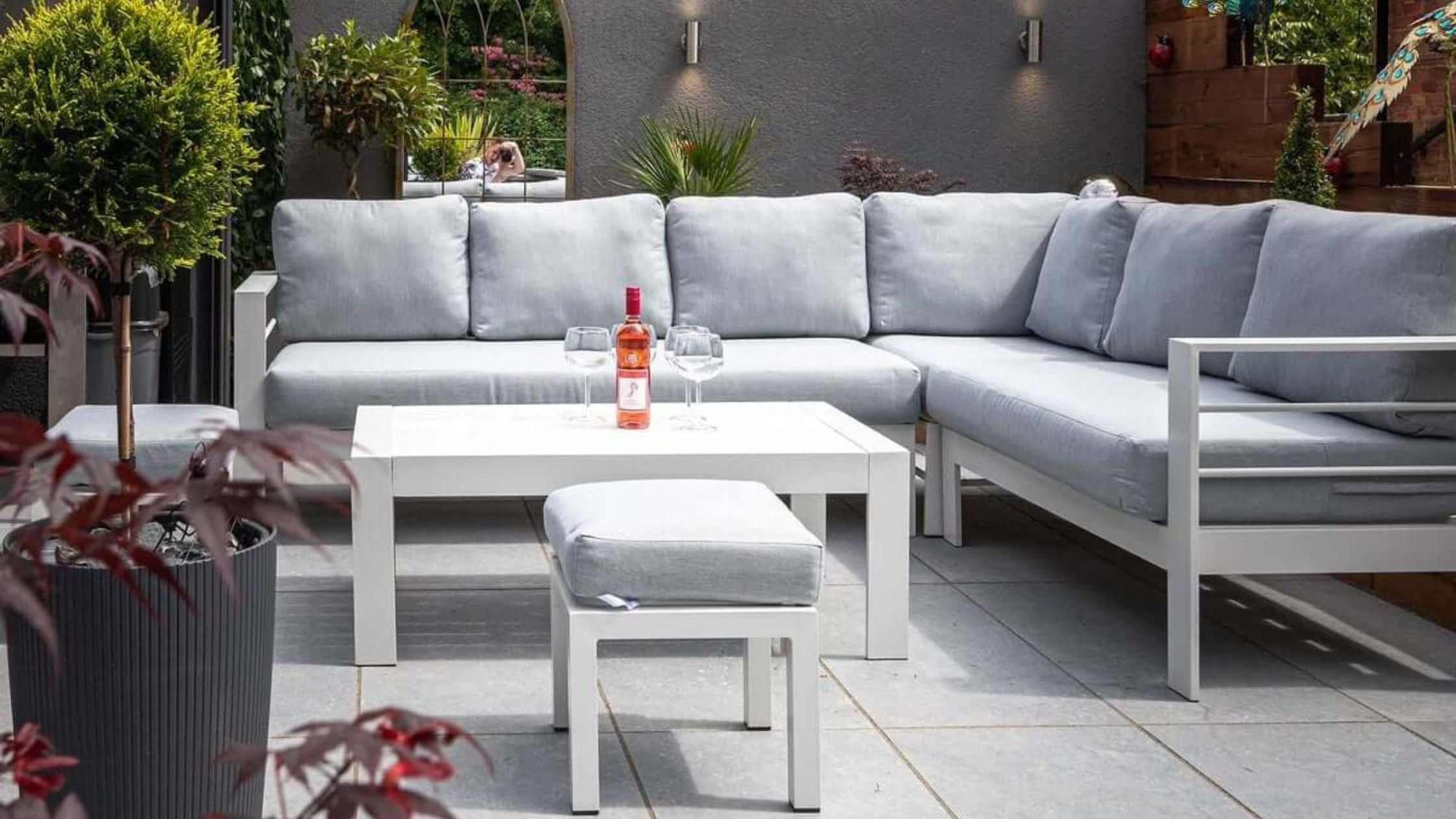 White aluminium corner sofa set with two stools and a coffee table.