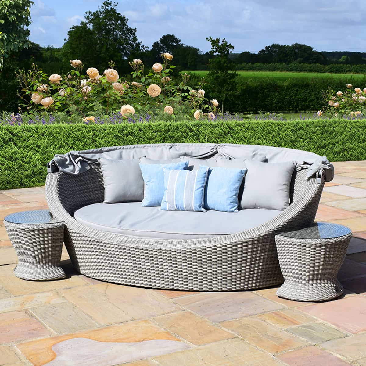 Light grey rattan daybed with retractable canvas hood and two matching side tables