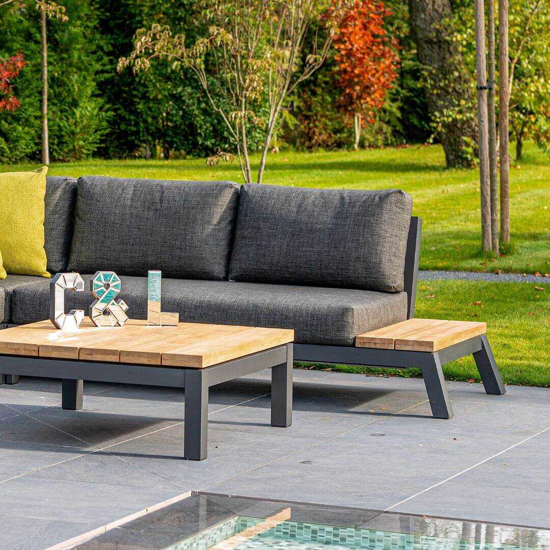 Close up of an anthracite aluminium corner sofa and matching coffee table with teak table top.