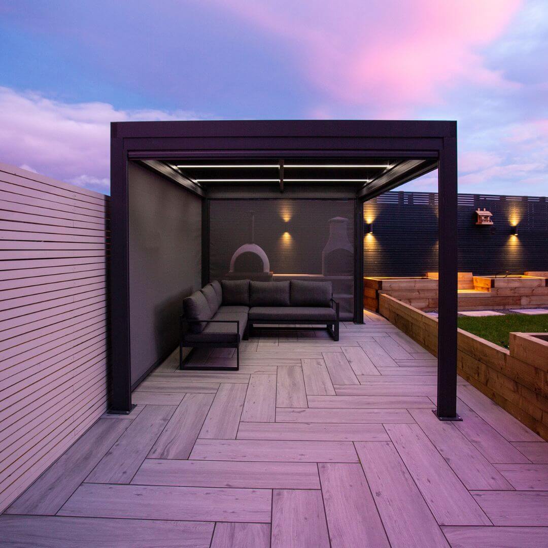 Side view of a grey aluminium pergola with Textilene pull down privacy screens attached.