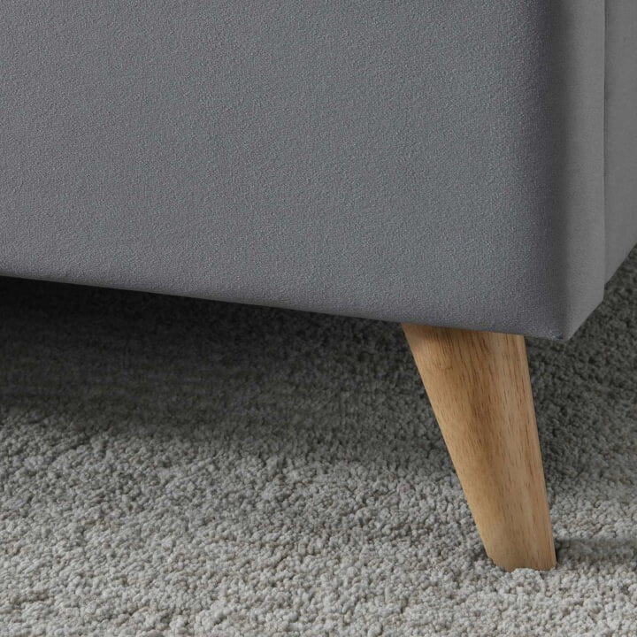 Close up of wooden feet of a grey fabric bed