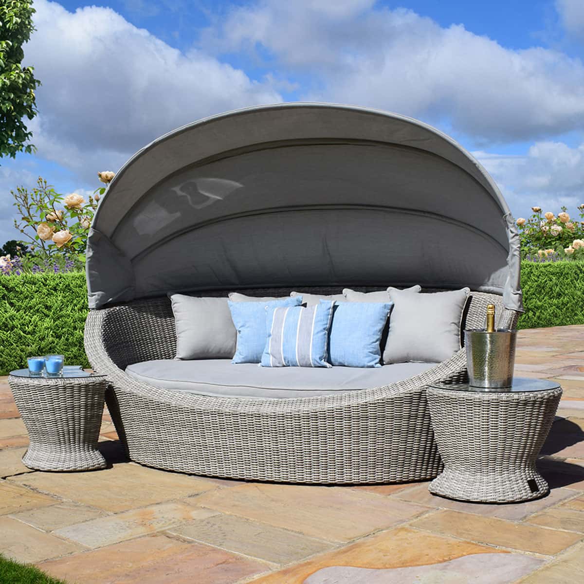 Light grey rattan daybed with retractable canvas hood and two matching side tables