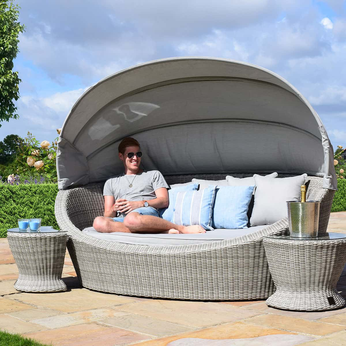 Light grey rattan daybed with retractable canvas hood and two matching side tables