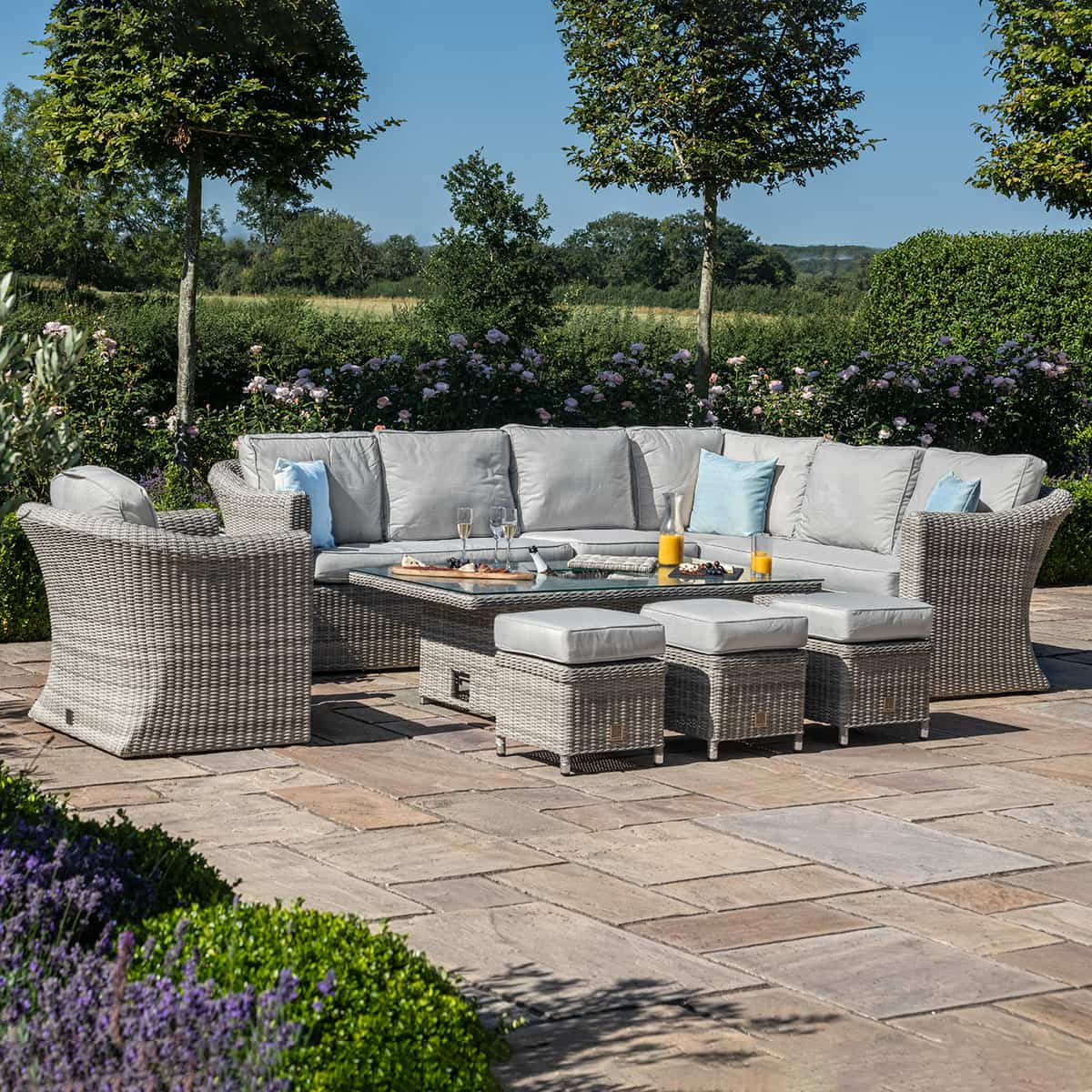 Light grey rattan corner sofa dining set with an armchair, three stools and a rectangular ice bucket rising table