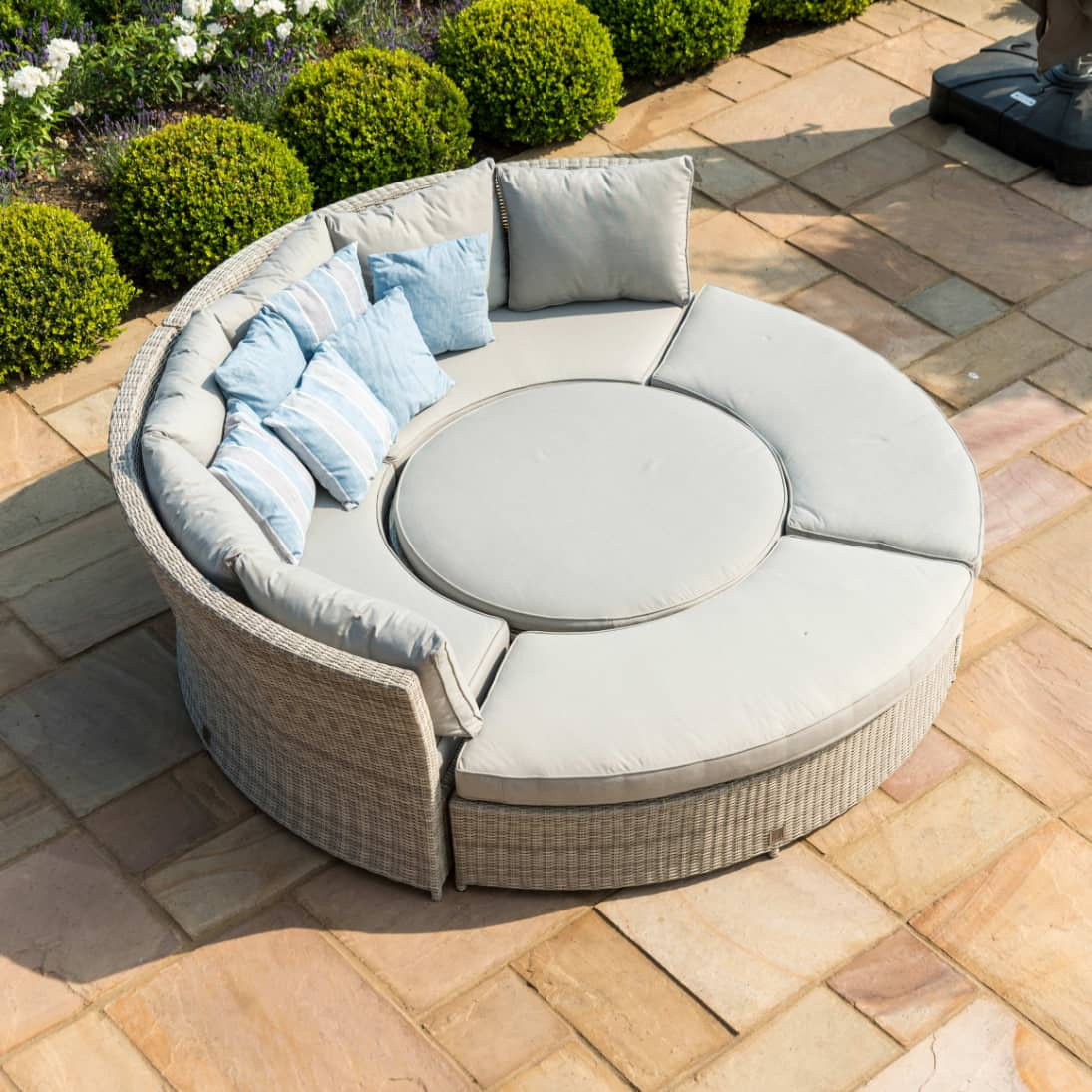 Light grey rattan lifestyle suite with a curved sofa, curved bench and a rising table - pushed together as a day bed