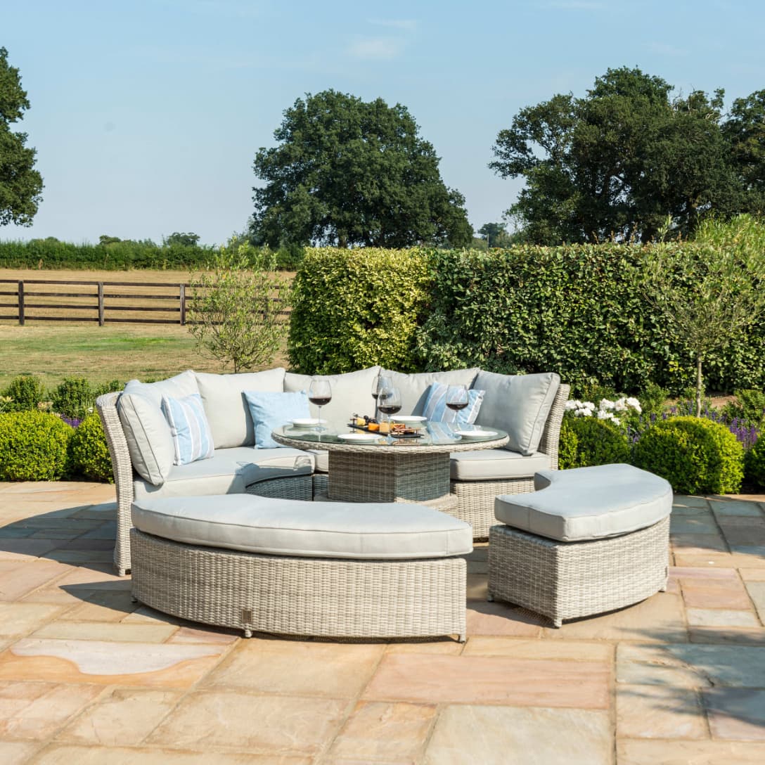 Light grey rattan lifestyle suite with a curved sofa, curved bench and a rising table