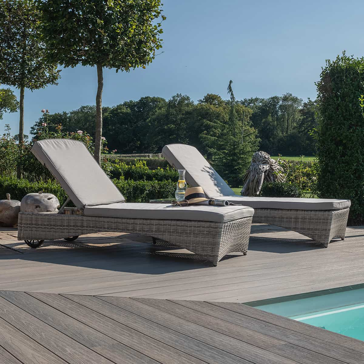 Light grey rattan sun lounger set with a small table