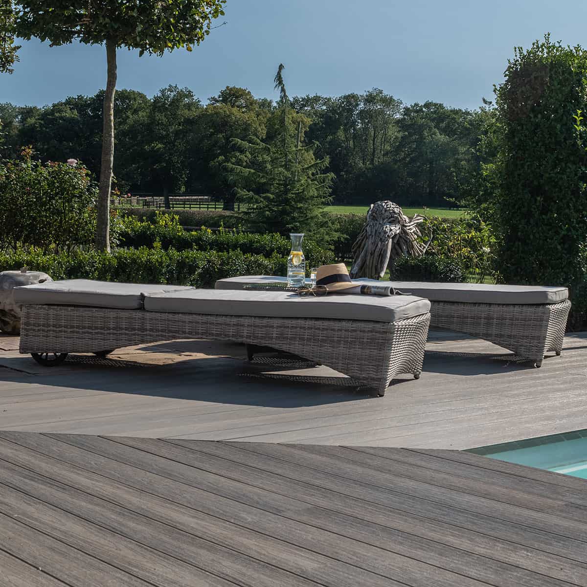 Light grey rattan sun lounger set with a small table