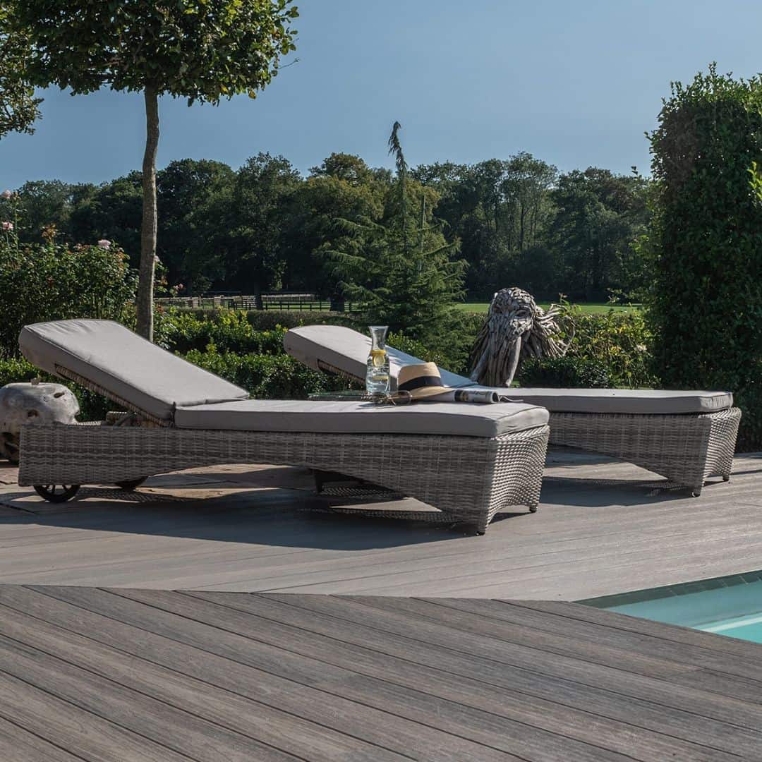 Light grey rattan sun lounger set with a small table