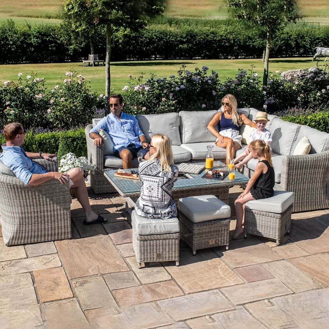 Light grey rattan corner sofa dining set with an armchair, three stools and a rectangular ice bucket rising table