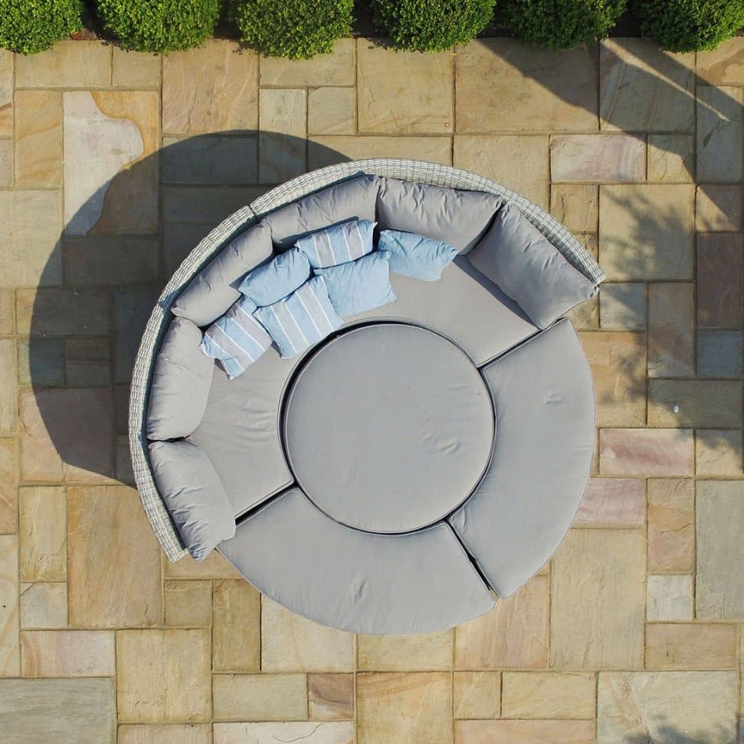 Overhead view of a light grey rattan lifestyle suite with a curved sofa, curved bench and a rising table - pushed together as a day bed