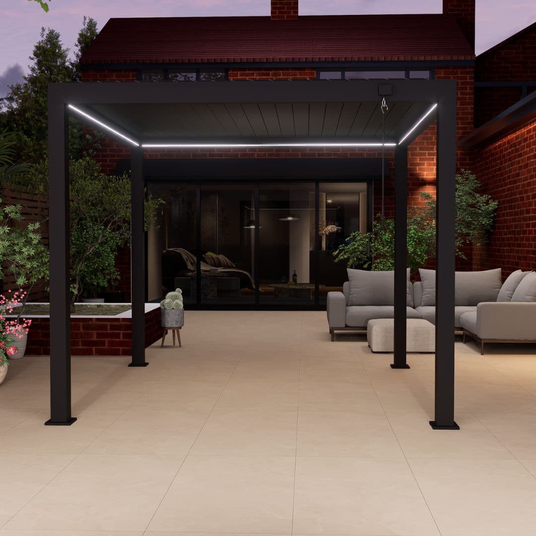 Front view of a grey aluminium pergola with louvred roof. The white LED lights underneath the roof panel are turned on.