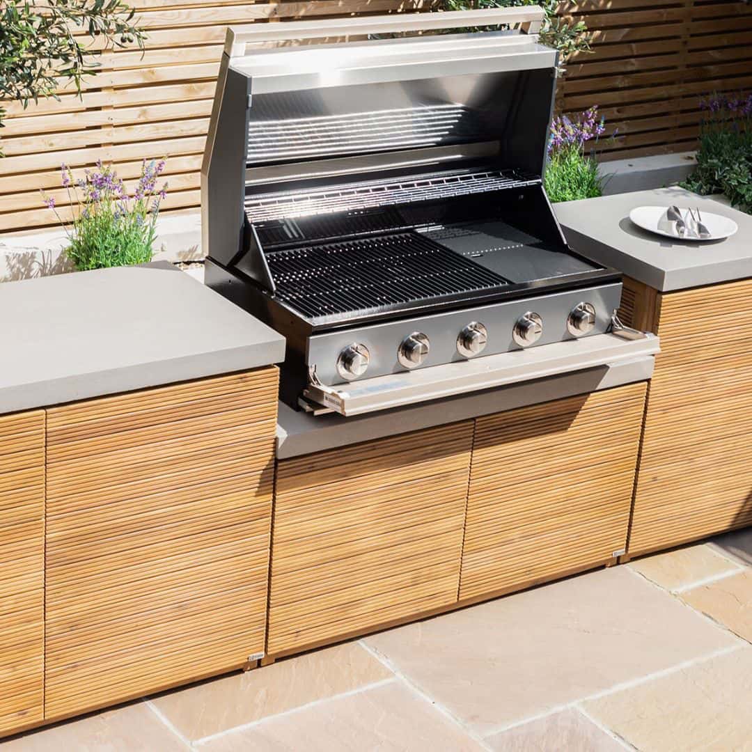 Acacia wood and a composite concrete worktop outdoor kitchen unit with bbq grill.