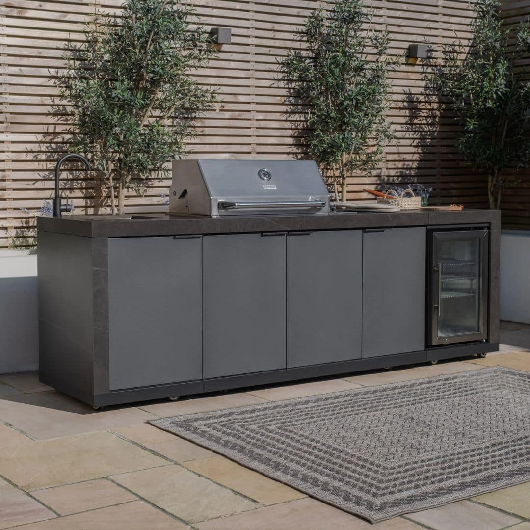 Grey outdoor kitchen unit with a bbq top unit, sink and fridge.