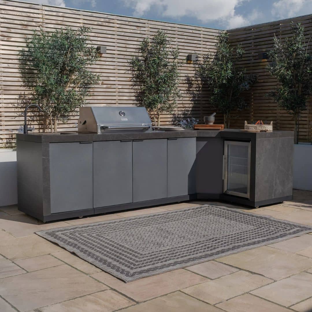 Grey outdoor kitchen unit with a bbq top unit, sink and fridge.