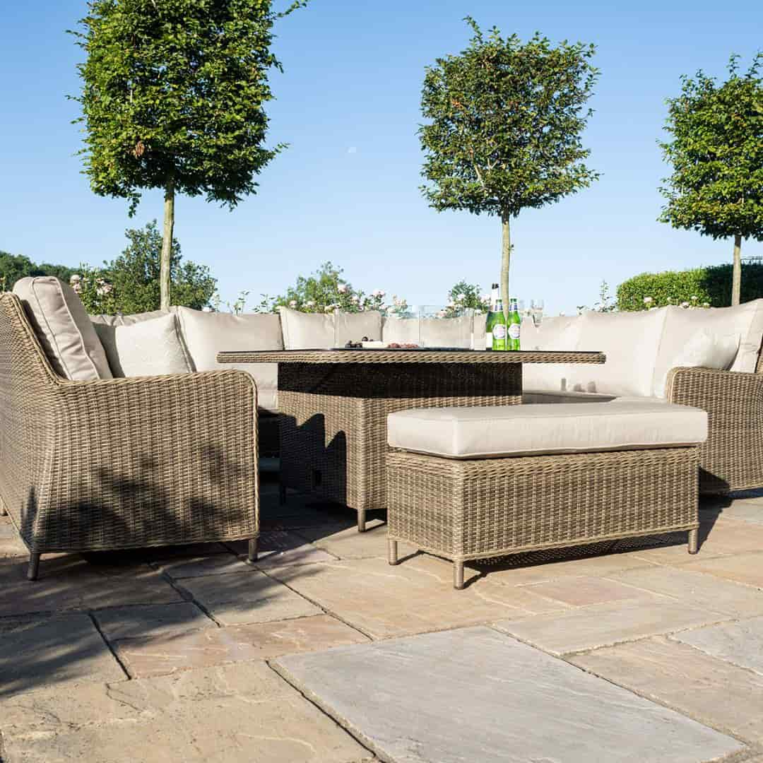 Low angle of a natural coloured rattan u shape sofa with matching bench and square fire pit table.