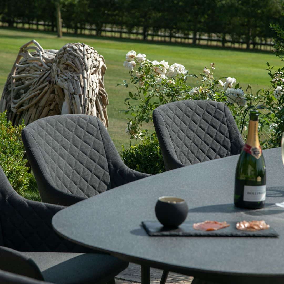 Close up of charcoal fabric dining chairs and oval dining table #colour_charcoal