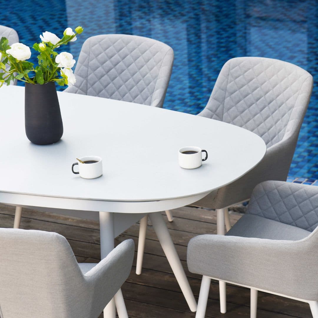 Close up of a white oval dining table and light grey fabric dining chairs #colour_lead chine