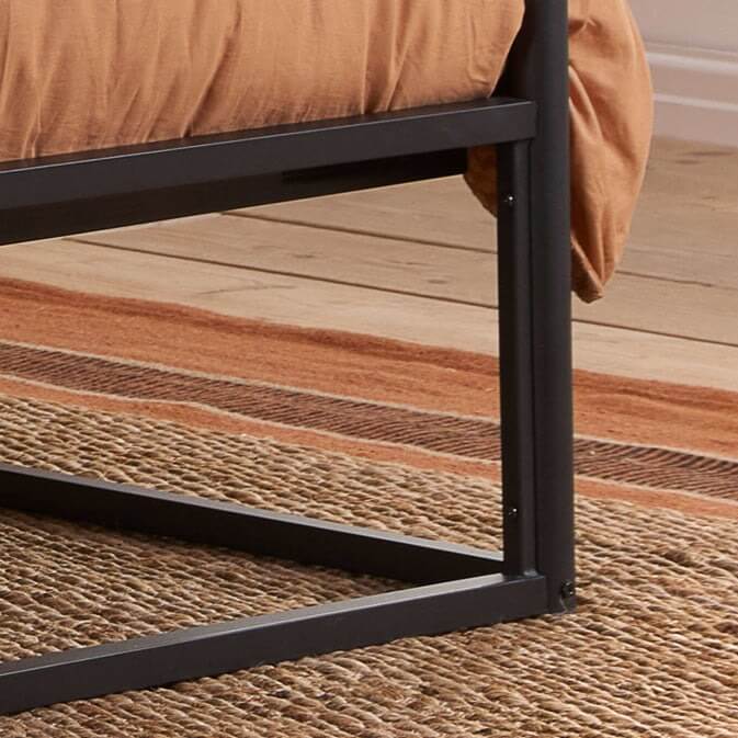 Close up of a black metal frame four poster bed.
