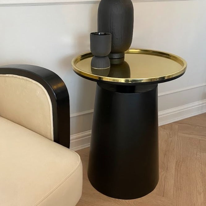 Black side table base with round gold table top.