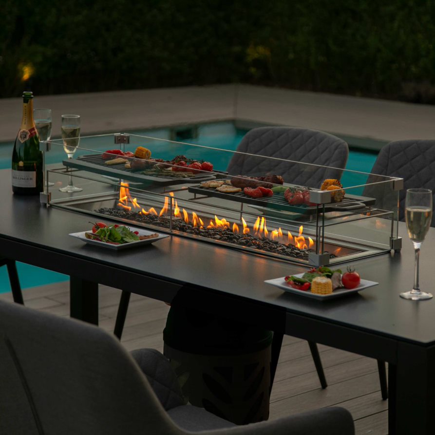 Close up of a fire pit dining table with fire pit turned on and dark grey fabric dining chairs #colour_flanelle
