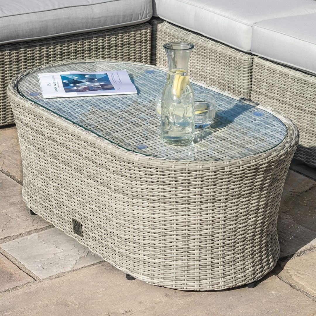 Light grey coloured rattan corner sofa with oval coffee table.