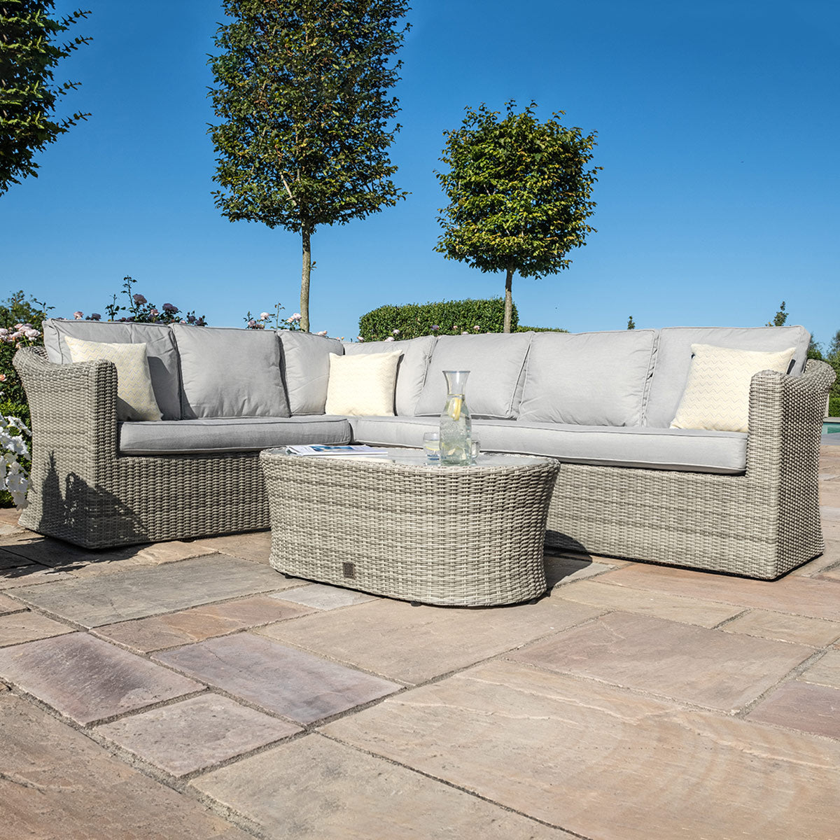 Light grey coloured rattan corner sofa with oval coffee table.