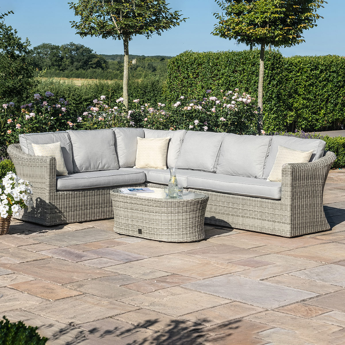 Light grey coloured rattan corner sofa with oval coffee table.