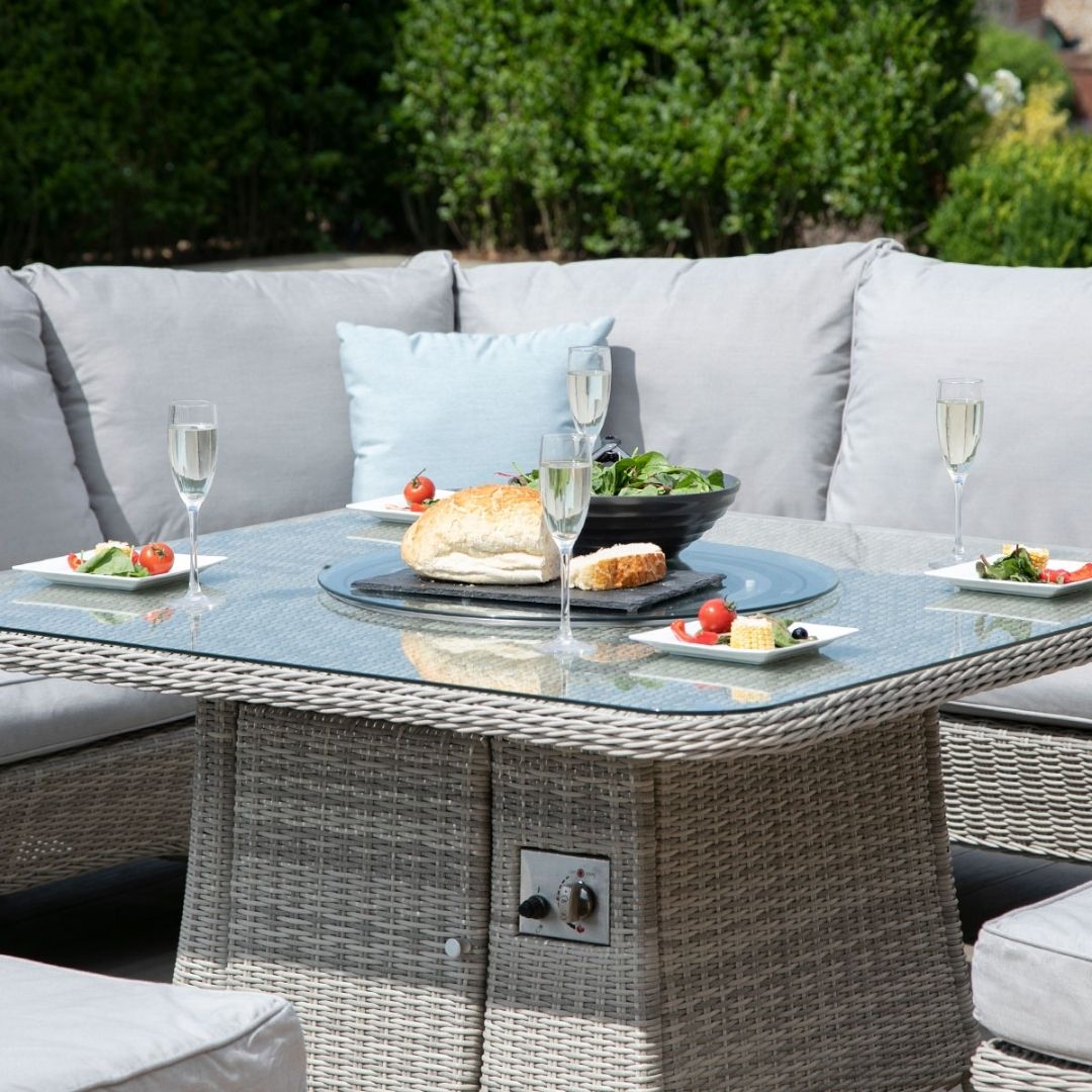 Light grey coloured rattan corner sofa with two matching benches and square fire pit table.