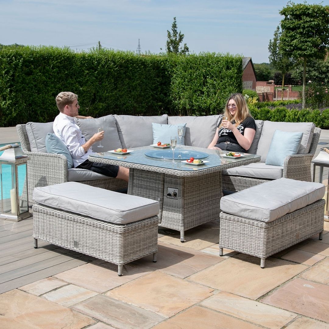 Light grey coloured rattan corner sofa with two matching benches and square fire pit table.