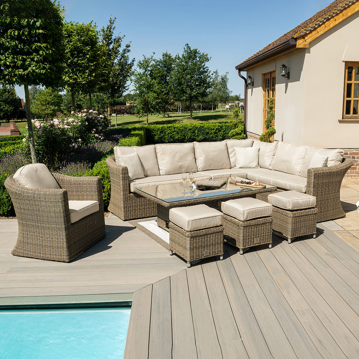 Natural coloured rattan corner sofa with an armchair, three stools and a rectangle rising table with ice bucket.