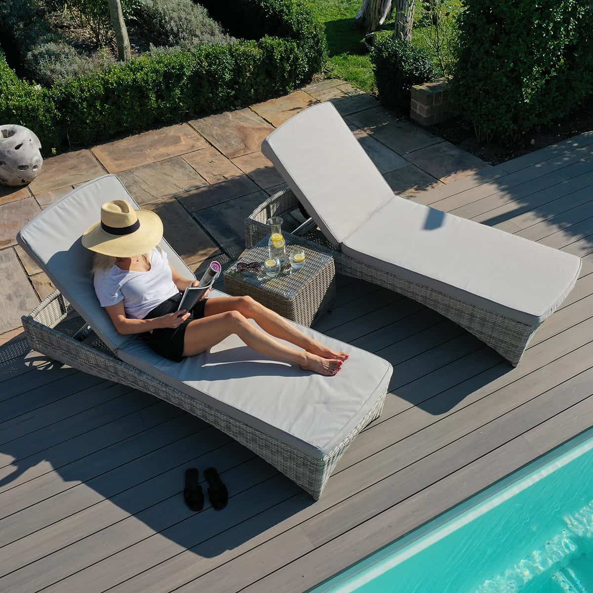 Light grey rattan sun lounger set with a small table
