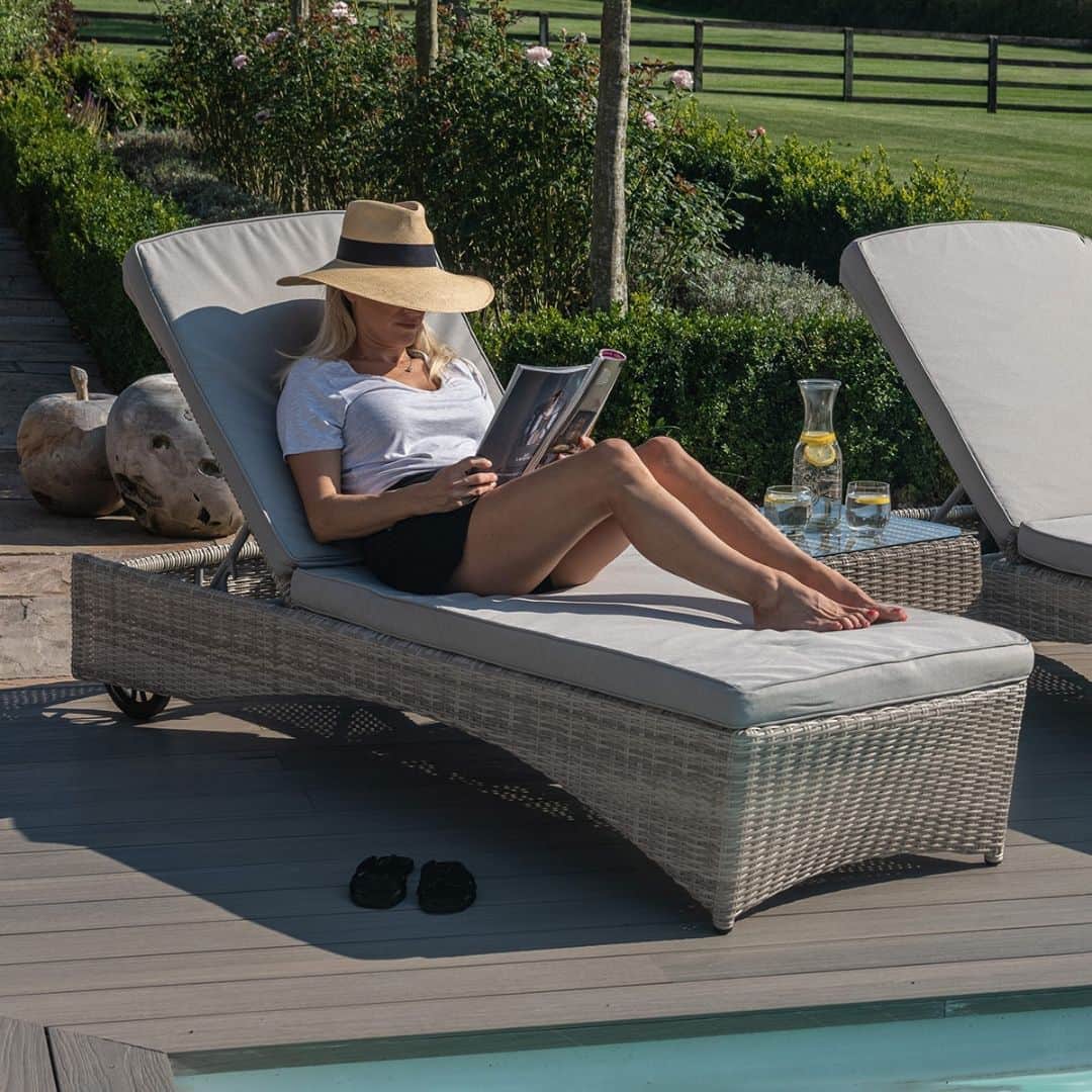 Light grey rattan sun lounger set with a small table