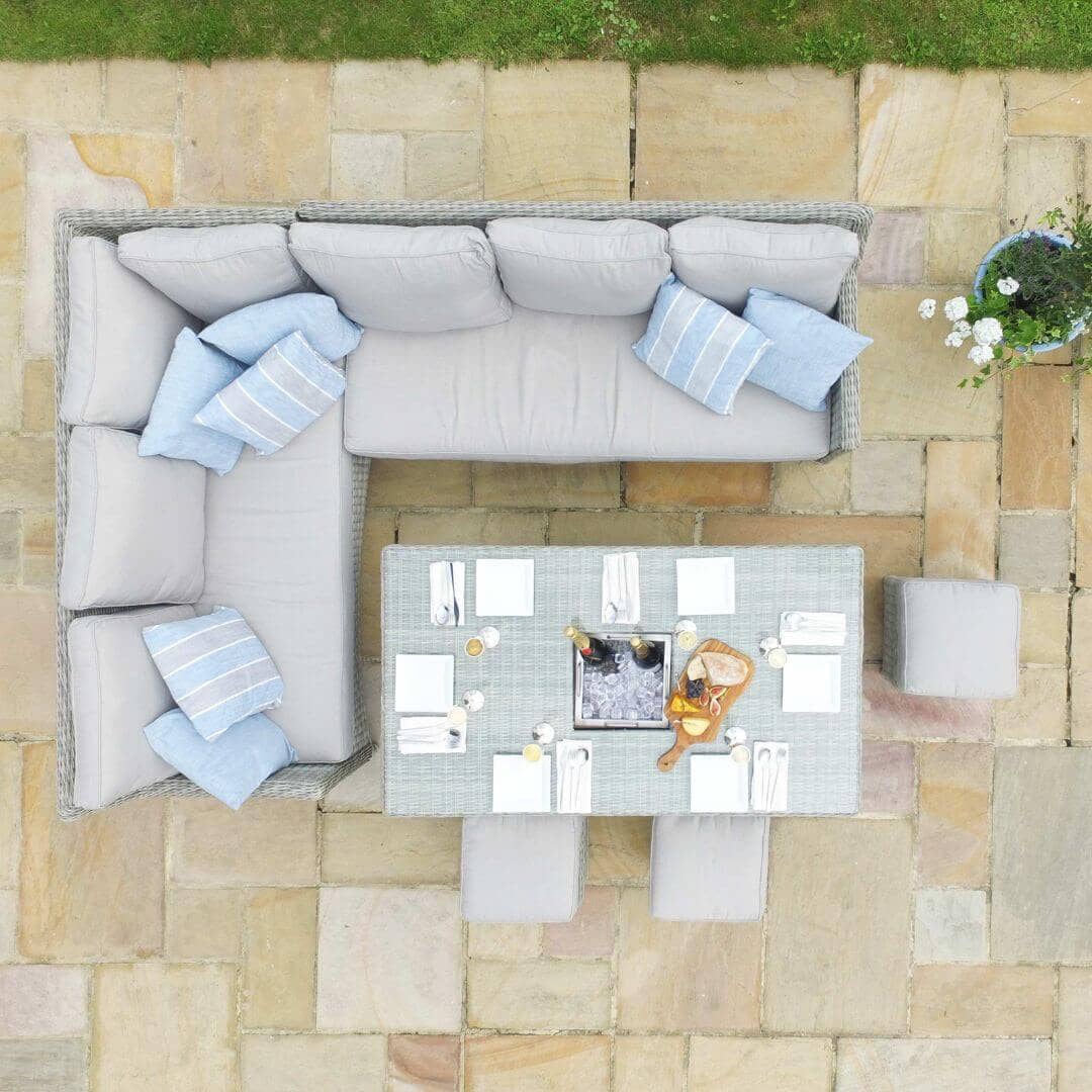 Overhead view of a light grey rattan corner sofa dining set with three stools and a rectangular ice bucket rising table