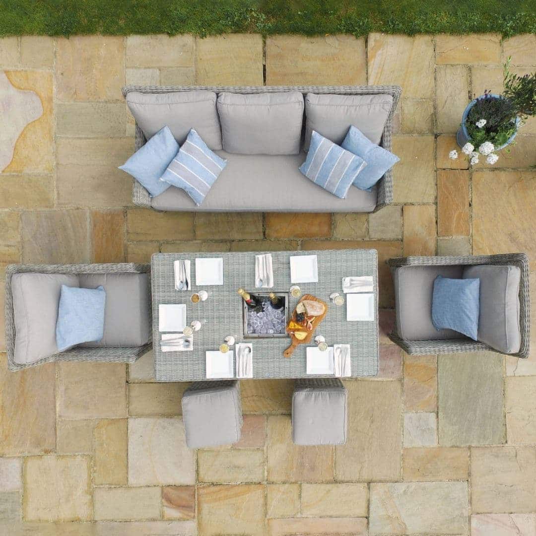 Overhead view of a light grey rattan sofa dining set with rectangular ice bucket rising table, two armchairs and two stools