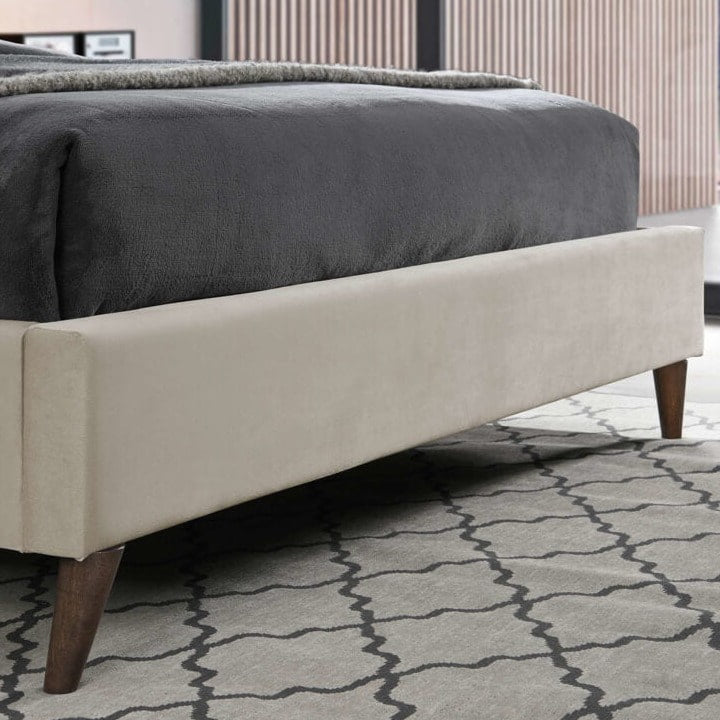 Close up of a stone fabric bed footboard and wood feet
