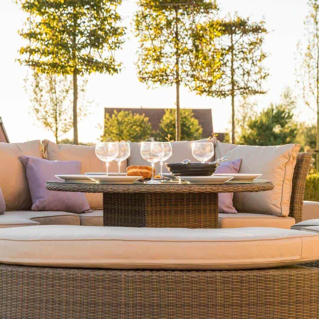 Close up of a natural coloured rattan rising table and curved bench.