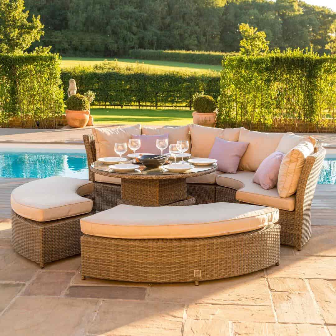 Side view of a natural coloured rattan curved casual dining set with two benches and a rising table.