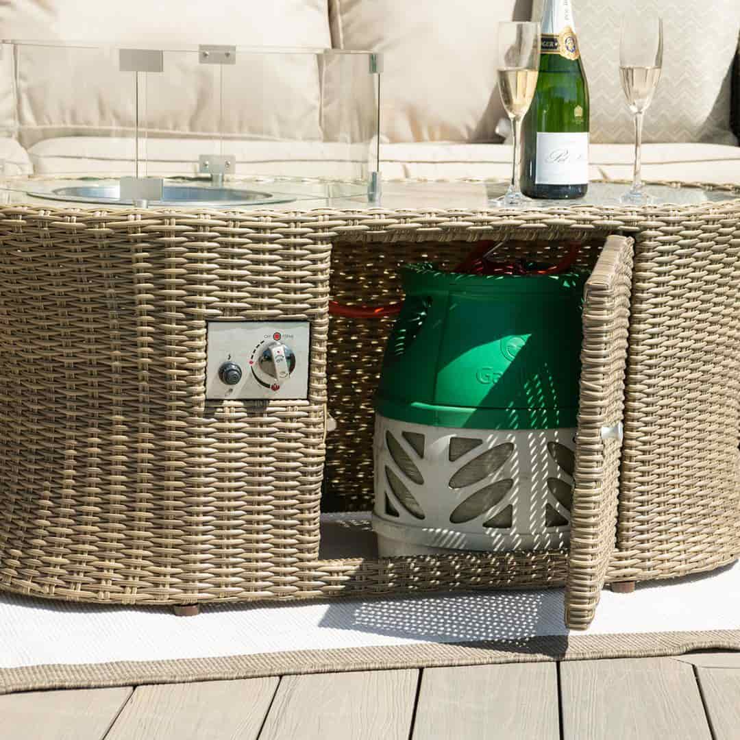 Close up of a natural coloured rattan oval fire pit coffee table with the door open.