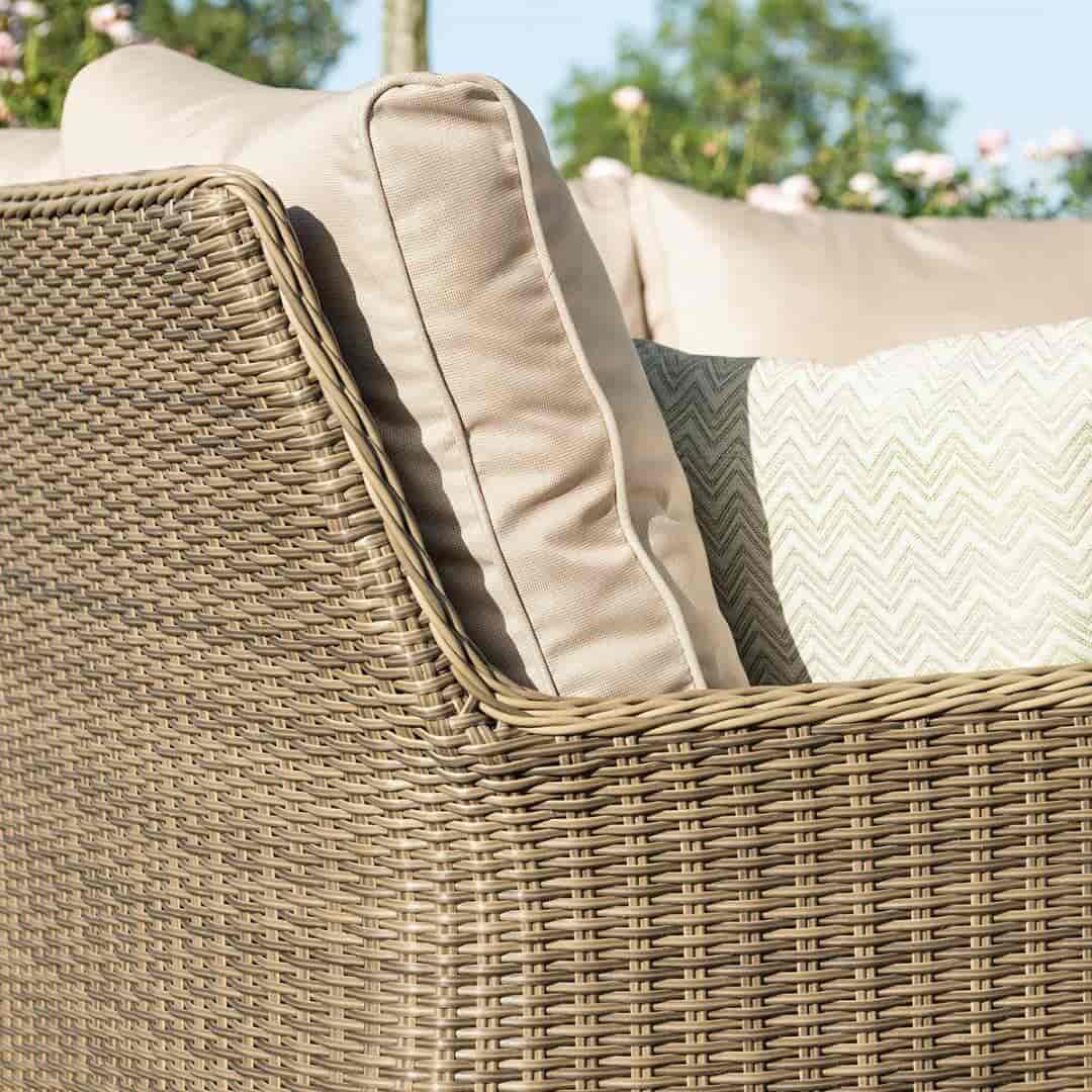 Close up of an arm and back of a natural coloured rattan corner sofa.