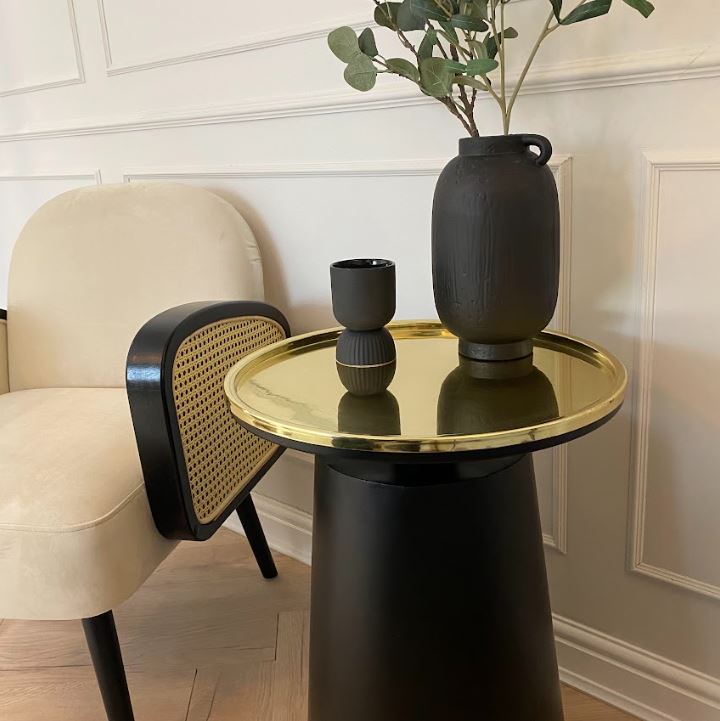 Close up of black side table base and round gold table top.