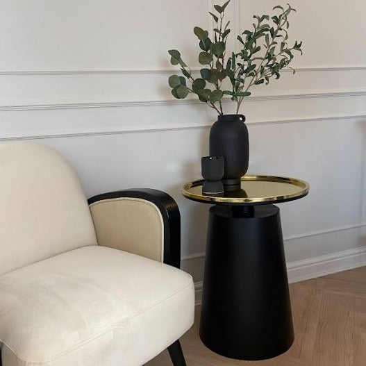 Black side table base with round gold table top.