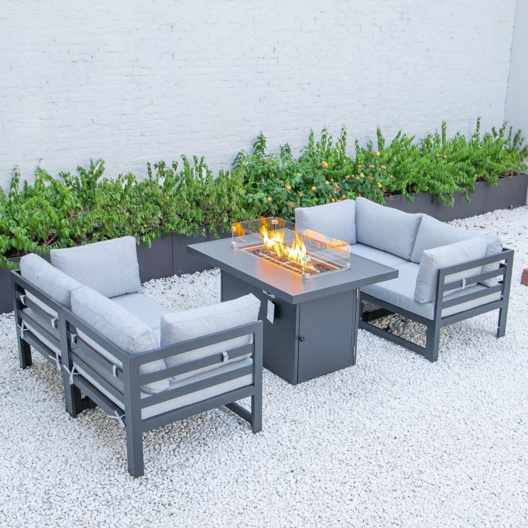 A grey aluminium 4 seat sofa set with fire pit table. The fire pit is turned on. 