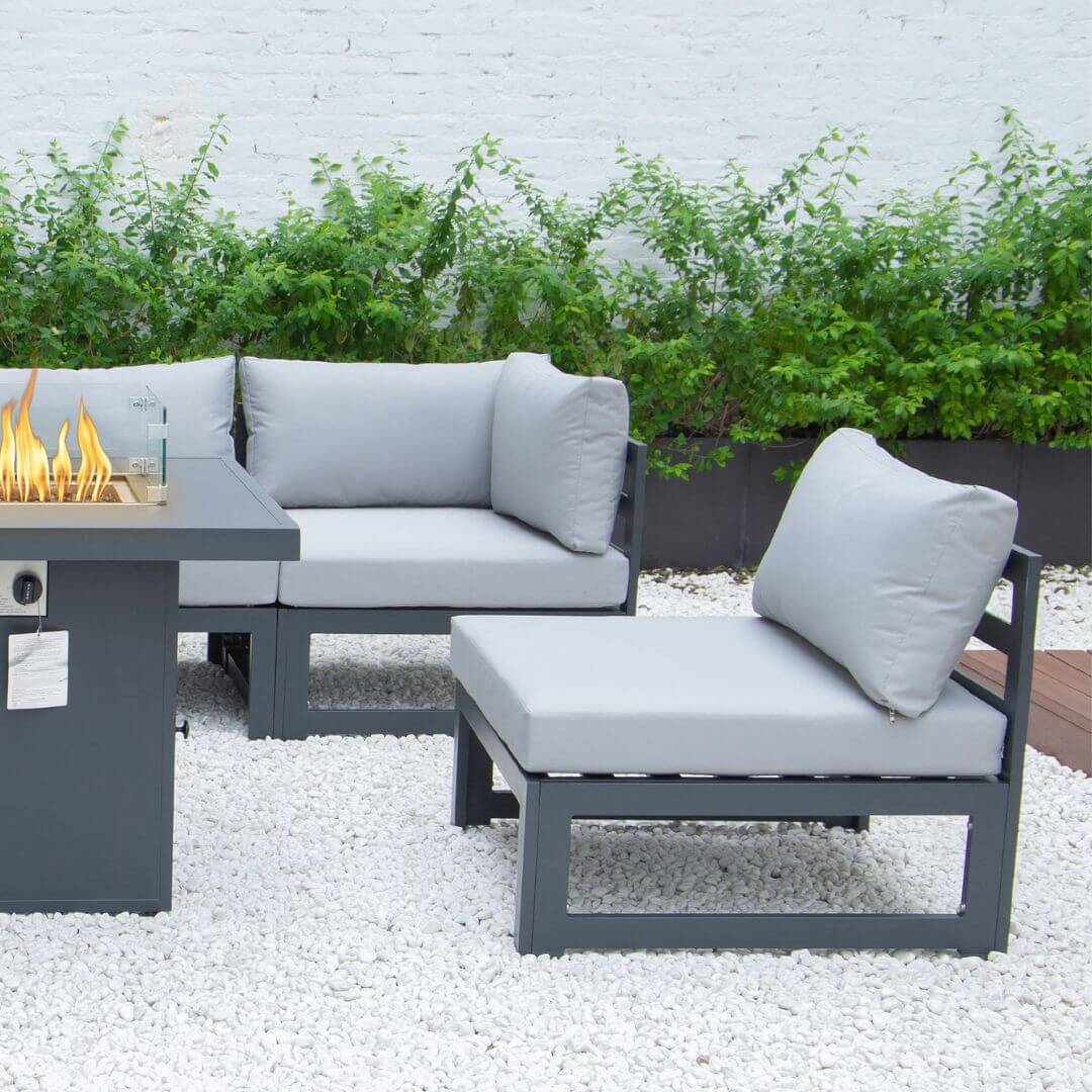 A close up of a single grey aluminium armchair with padded seat and back cushions. The corner of the fire pit table and 4 seat sofa is in the frame.