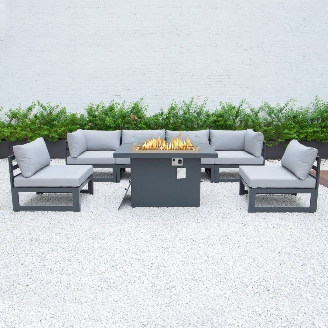 A grey aluminium 6 seat sofa set with fire pit table. A 4 seat sofa is at the back, a single armchair on each side and a matching fire pit table in the centre. The fire pit is turned on.
