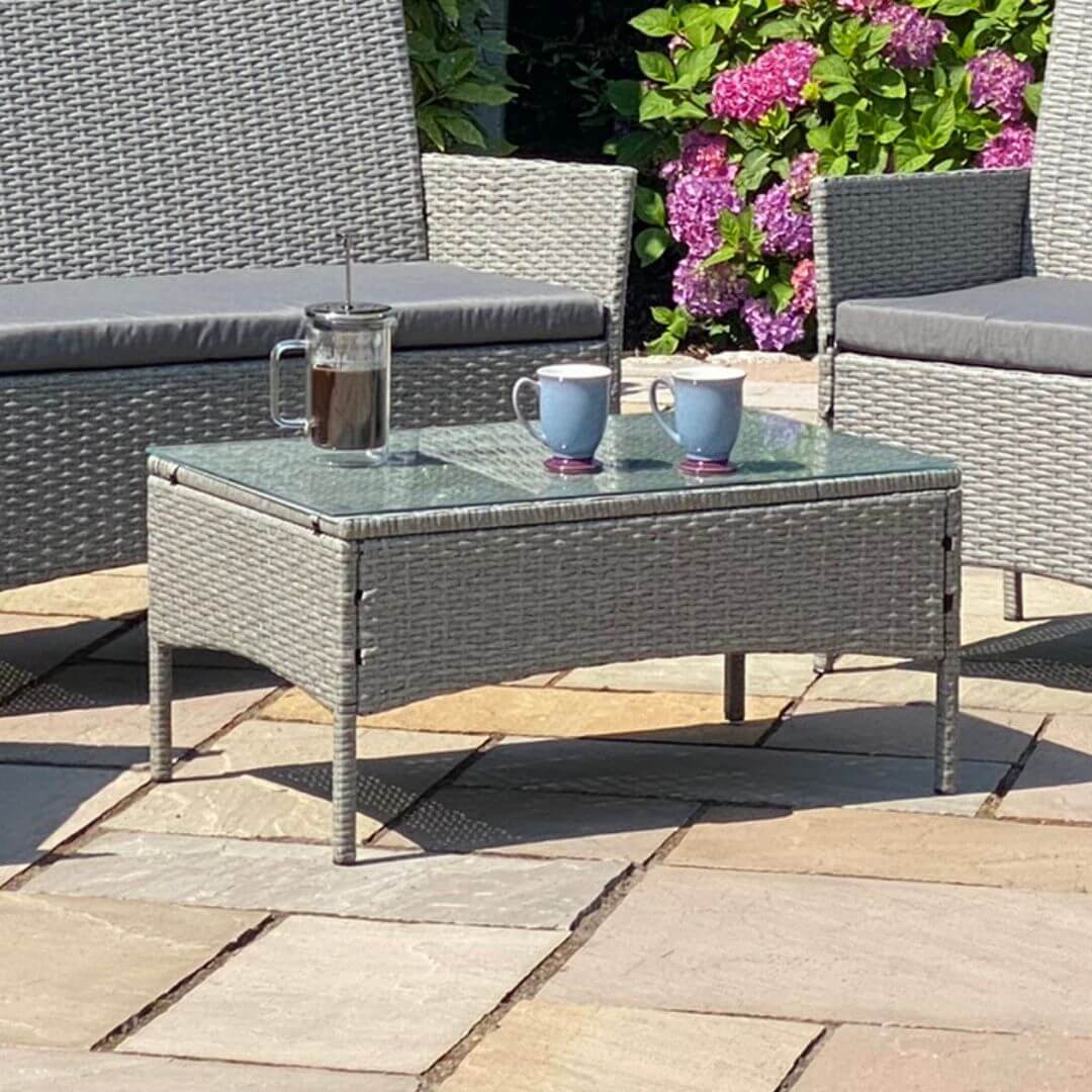 Close up of a light grey rattan rectangle coffee table with tempered glass table top.