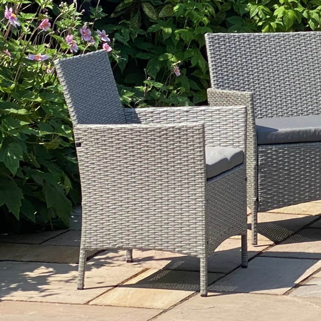 Close up of a light grey rattan chair with padded seat cushion.