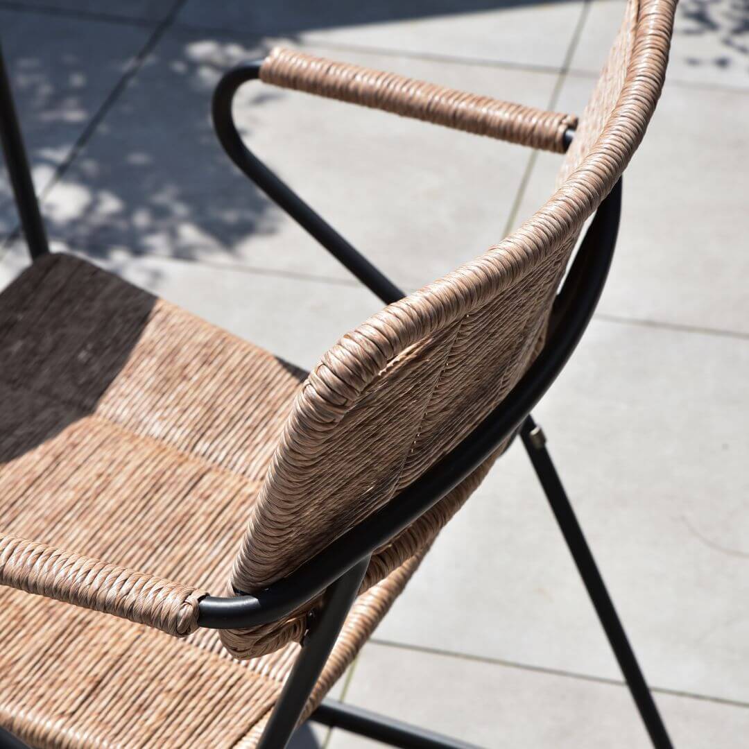 Close up of a wicker dining chair and stainless steel base.