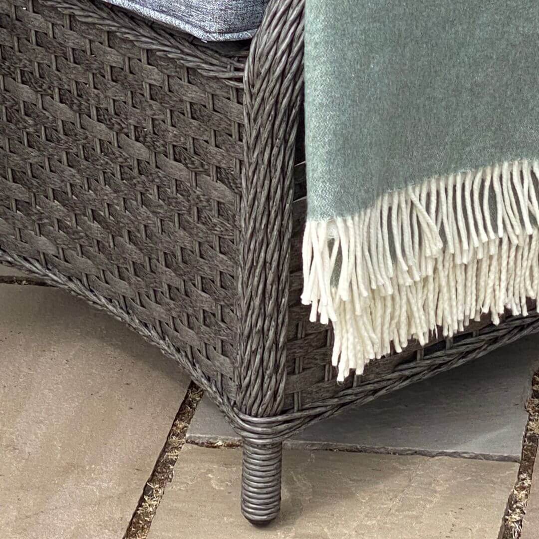 Close up of feet of a dark grey rattan armchair.