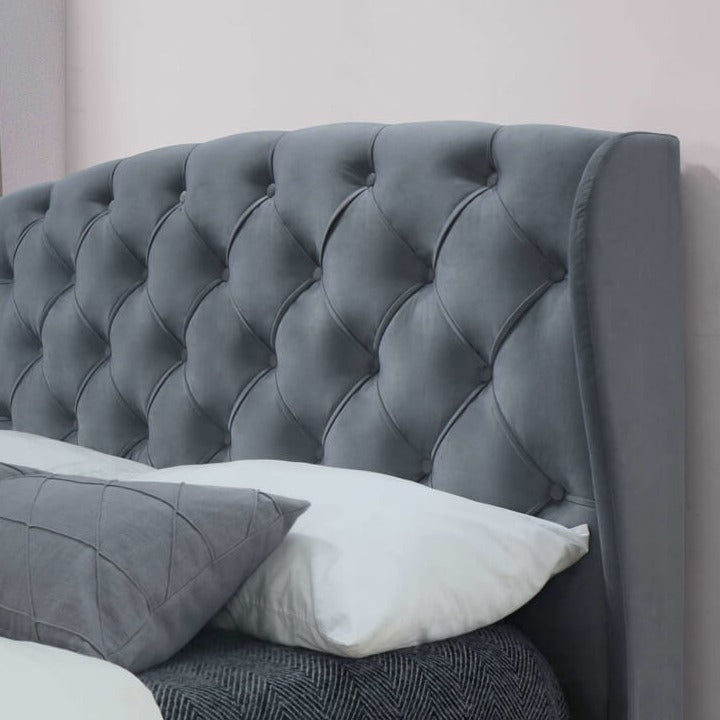Close up of a grey fabric bed headboard.